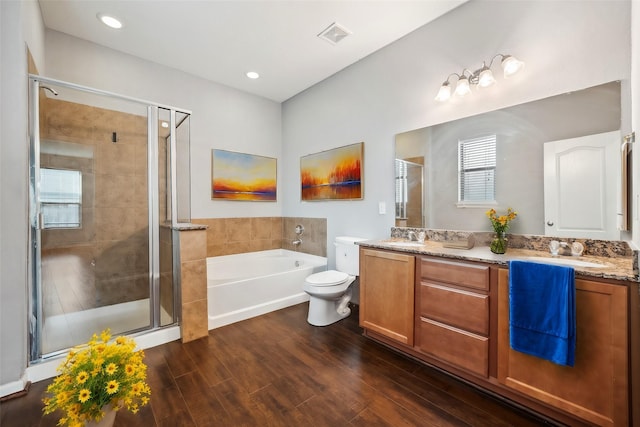 bathroom with a garden tub, double vanity, a stall shower, a sink, and wood finished floors