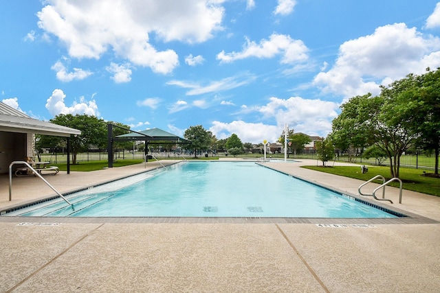 pool with a patio area and fence