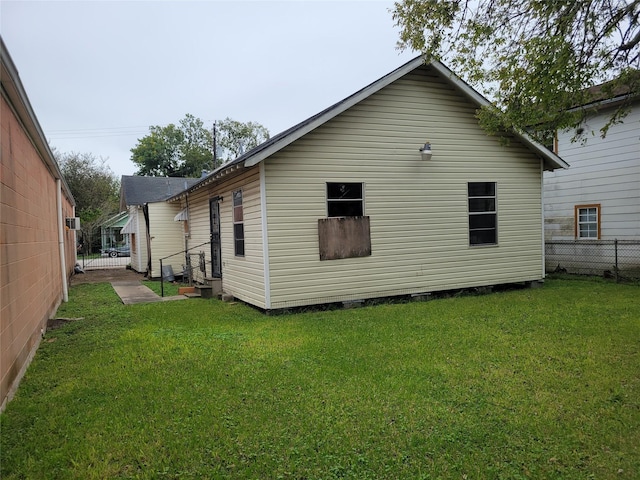 back of house with entry steps, fence, and a lawn