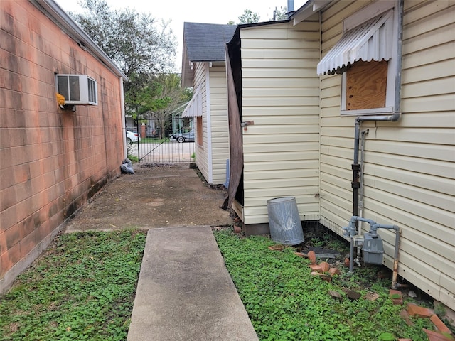 view of property exterior featuring roof with shingles, a wall unit AC, and fence