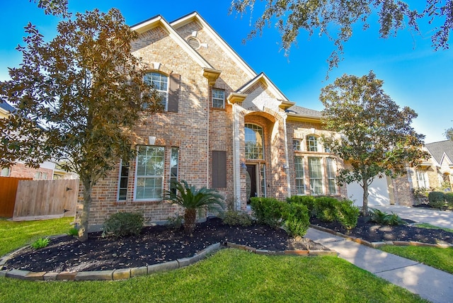 view of front of house featuring brick siding, fence, a garage, driveway, and a front lawn