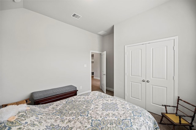 bedroom featuring a closet, visible vents, carpet flooring, vaulted ceiling, and baseboards