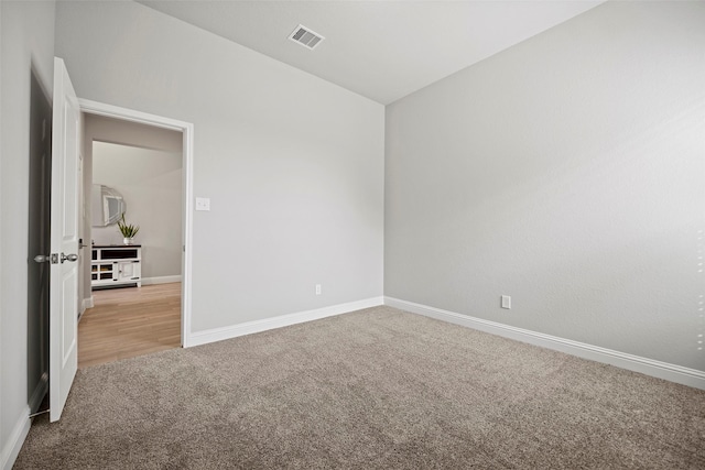 empty room with carpet floors, baseboards, and visible vents