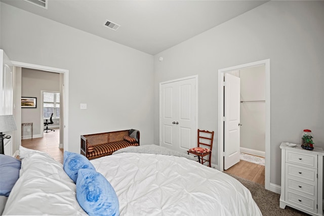 bedroom with baseboards, visible vents, a closet, and wood finished floors