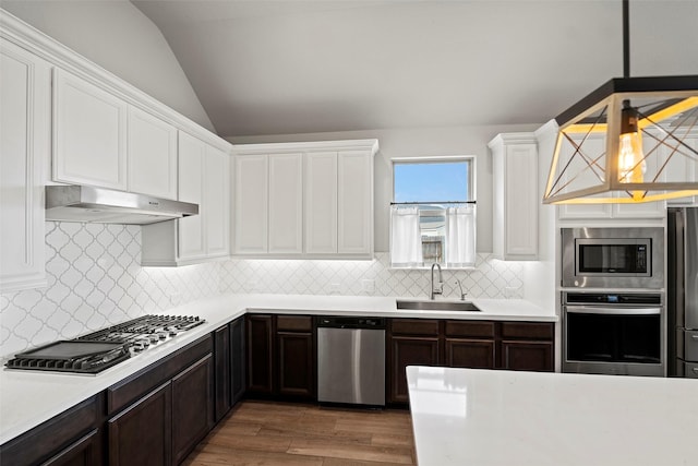 kitchen with light countertops, appliances with stainless steel finishes, white cabinetry, a sink, and under cabinet range hood