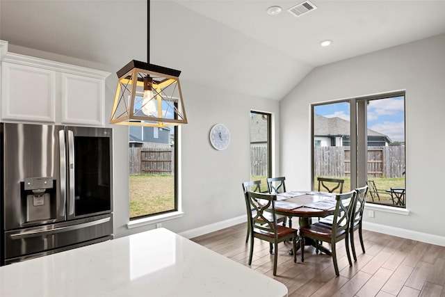 dining room featuring vaulted ceiling, wood finished floors, visible vents, and baseboards