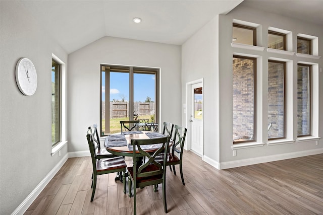 dining area with baseboards, vaulted ceiling, and wood finished floors