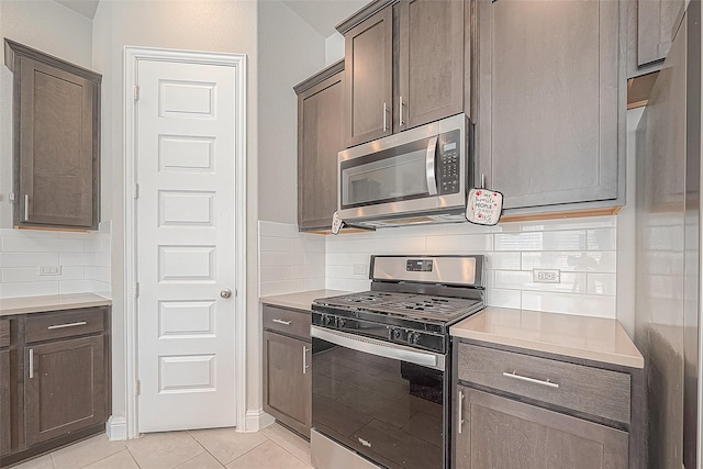 kitchen with stainless steel appliances, light countertops, backsplash, and light tile patterned floors