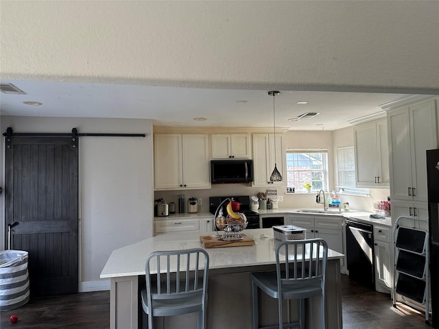 kitchen with a kitchen island, a sink, visible vents, light countertops, and black appliances