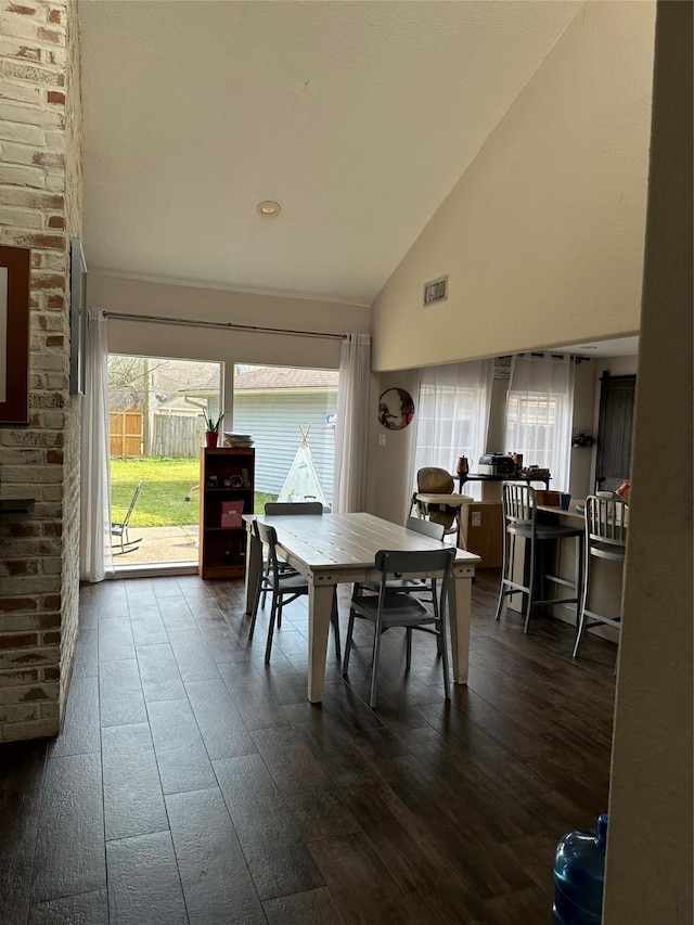 dining area featuring high vaulted ceiling, dark wood-type flooring, and visible vents