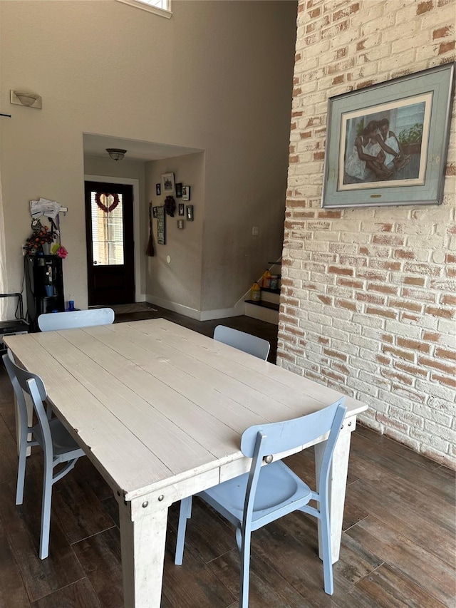 dining area with stairs, brick wall, wood finished floors, and baseboards