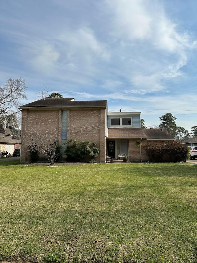 rear view of house featuring brick siding and a yard