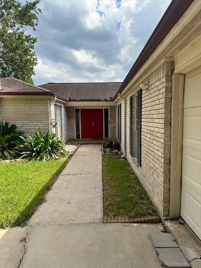 doorway to property featuring a shingled roof and brick siding