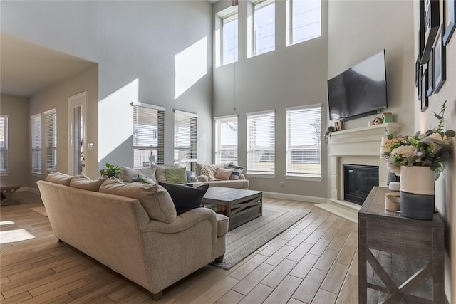 living room with a glass covered fireplace, light wood-style flooring, and baseboards