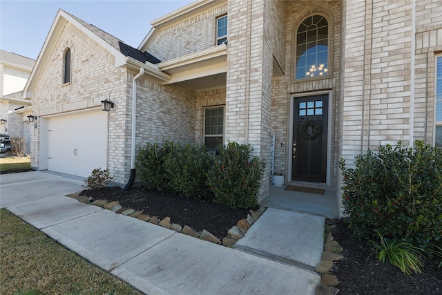 entrance to property featuring a garage, concrete driveway, and brick siding