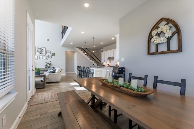 dining space featuring baseboards, visible vents, stairs, light wood-type flooring, and recessed lighting