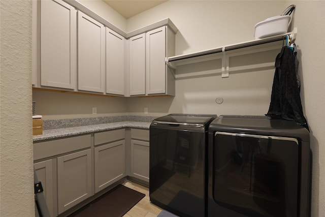 washroom featuring washing machine and dryer and cabinet space