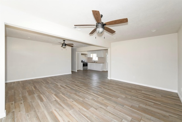 unfurnished living room with visible vents, light wood finished floors, a ceiling fan, and baseboards