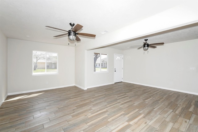 unfurnished room featuring a ceiling fan, visible vents, baseboards, and wood finished floors