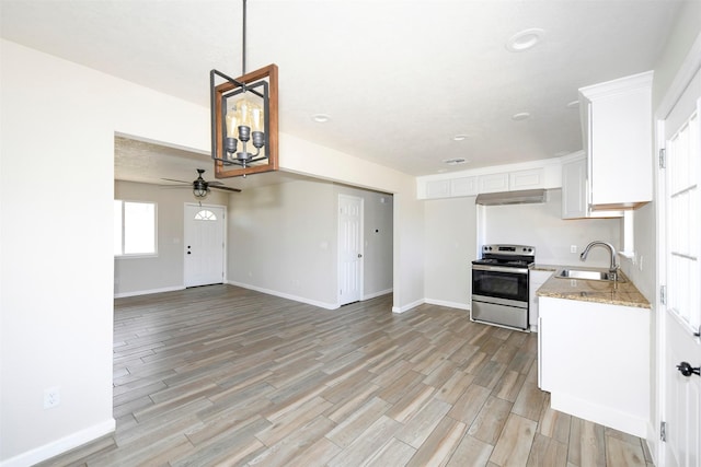 kitchen featuring electric range, white cabinets, a sink, light wood-type flooring, and baseboards