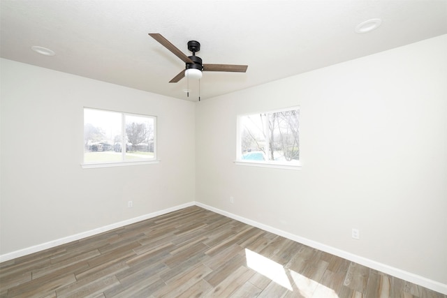 empty room featuring a healthy amount of sunlight, baseboards, and wood finished floors