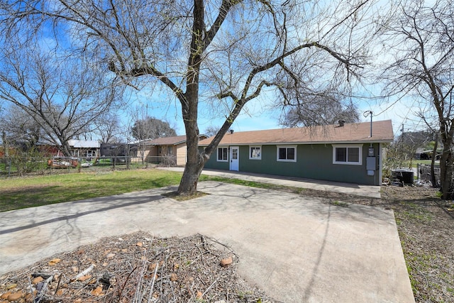 view of front facade featuring concrete driveway, cooling unit, fence, and a front yard