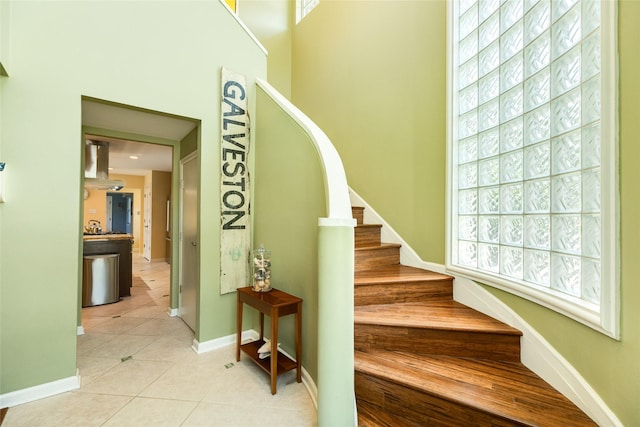 staircase with a towering ceiling, baseboards, and tile patterned floors