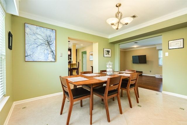 dining space featuring light tile patterned floors, visible vents, baseboards, crown molding, and a chandelier