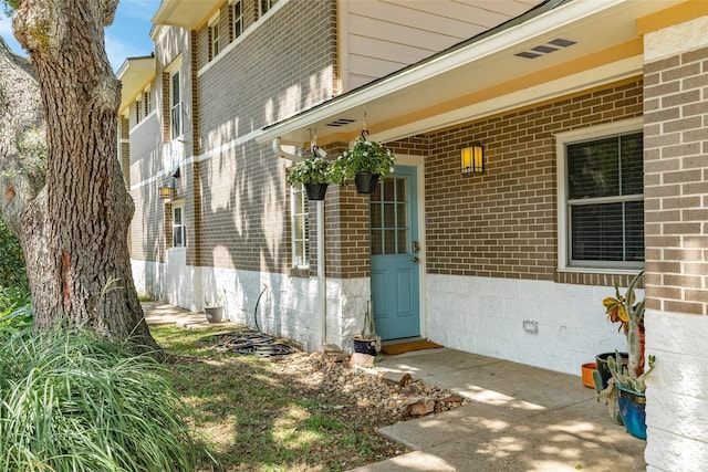 view of exterior entry featuring brick siding