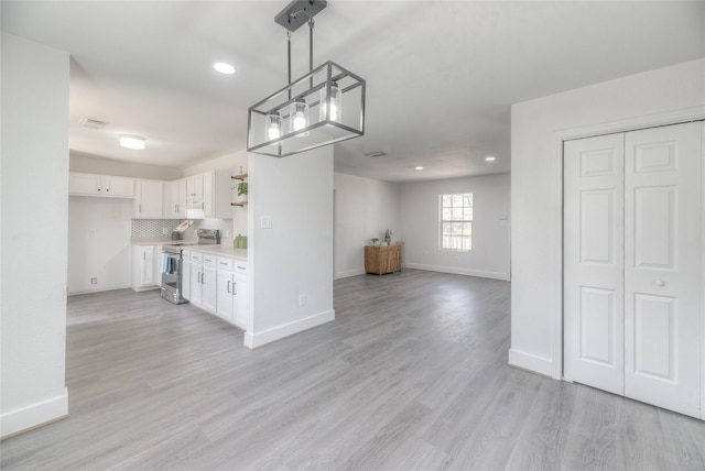 kitchen with light countertops, light wood-style flooring, decorative backsplash, stainless steel range with electric cooktop, and white cabinetry