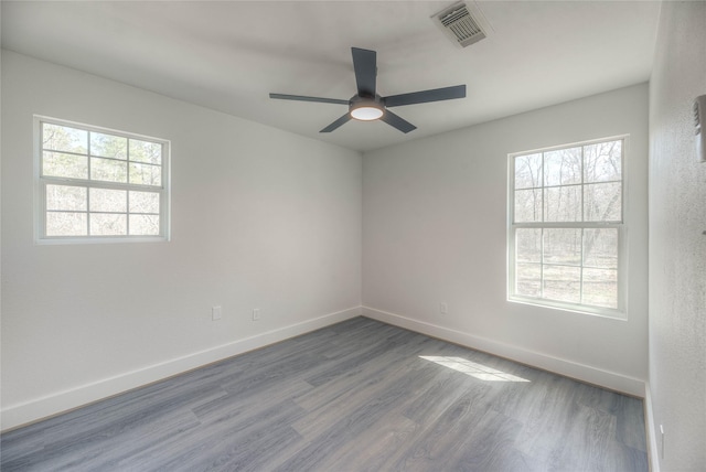 unfurnished room with a ceiling fan, visible vents, baseboards, and wood finished floors