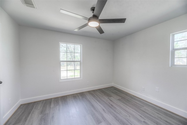 unfurnished room featuring baseboards, visible vents, ceiling fan, and wood finished floors