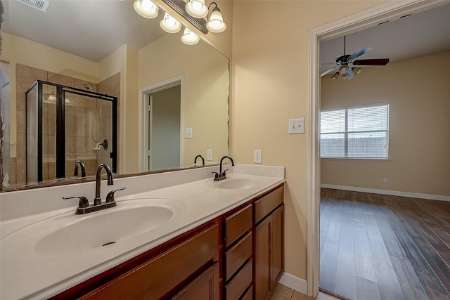 bathroom with double vanity, a stall shower, ceiling fan, and a sink