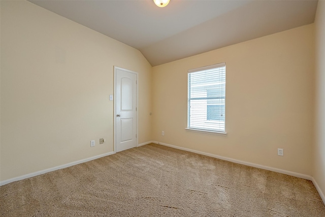 carpeted spare room with vaulted ceiling and baseboards