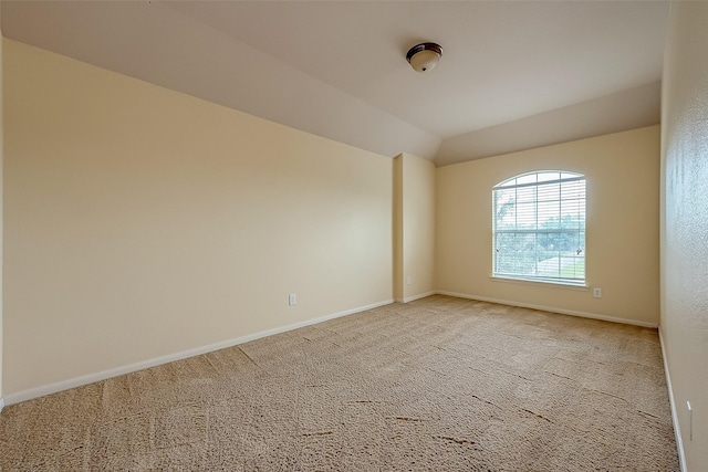 empty room featuring baseboards, light carpet, and vaulted ceiling