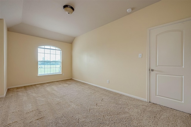 carpeted empty room featuring baseboards and lofted ceiling