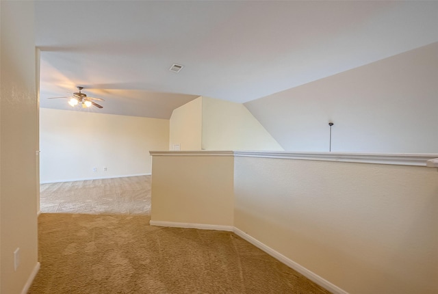 unfurnished room with a ceiling fan, visible vents, baseboards, lofted ceiling, and light colored carpet