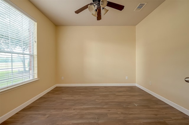 empty room with ceiling fan, visible vents, baseboards, and wood finished floors