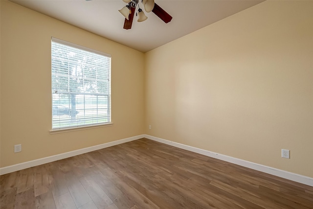 unfurnished room with a ceiling fan, dark wood-type flooring, and baseboards