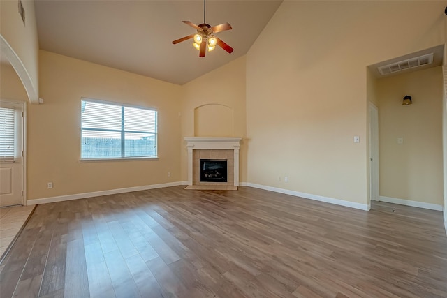 unfurnished living room with a fireplace, wood finished floors, visible vents, and high vaulted ceiling