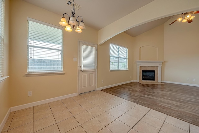 interior space with visible vents, light wood-style flooring, baseboards, lofted ceiling, and a tile fireplace