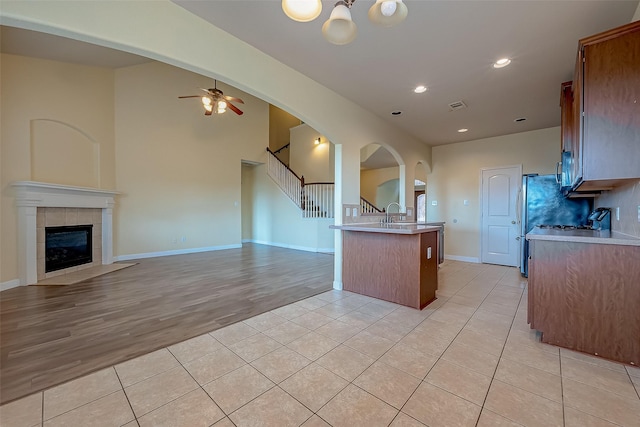 kitchen featuring light tile patterned floors, open floor plan, a tiled fireplace, and light countertops