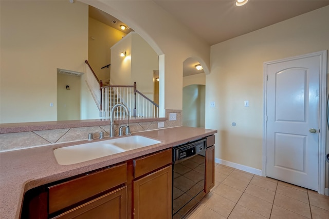 kitchen with light countertops, black dishwasher, brown cabinets, light tile patterned flooring, and a sink