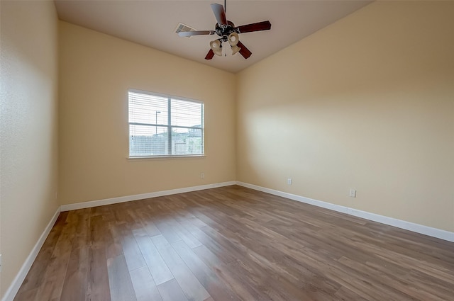 spare room featuring visible vents, baseboards, wood finished floors, and a ceiling fan