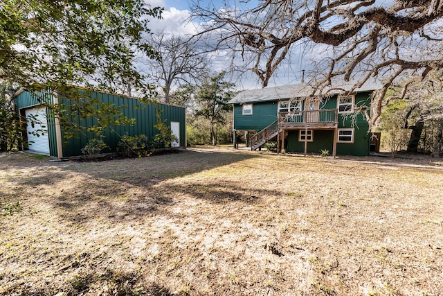 rear view of house featuring a garage, an outbuilding, a wooden deck, and stairs