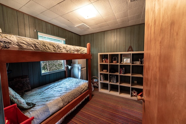 bedroom with carpet flooring, wood walls, and visible vents