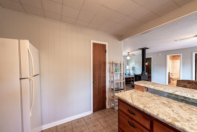 kitchen with freestanding refrigerator, a wood stove, light countertops, and baseboards