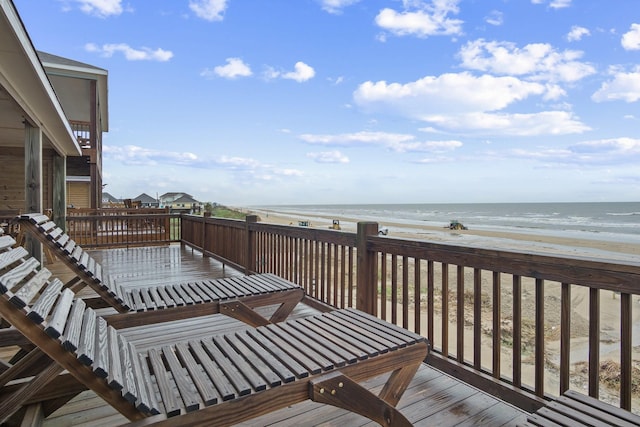 wooden terrace featuring a water view and a view of the beach