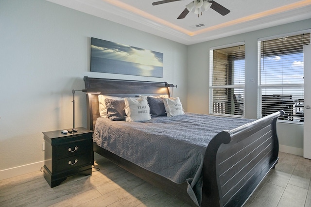 bedroom featuring baseboards, visible vents, a raised ceiling, and wood finished floors