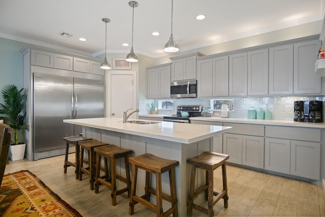 kitchen with light countertops, stainless steel appliances, gray cabinetry, a kitchen bar, and a sink